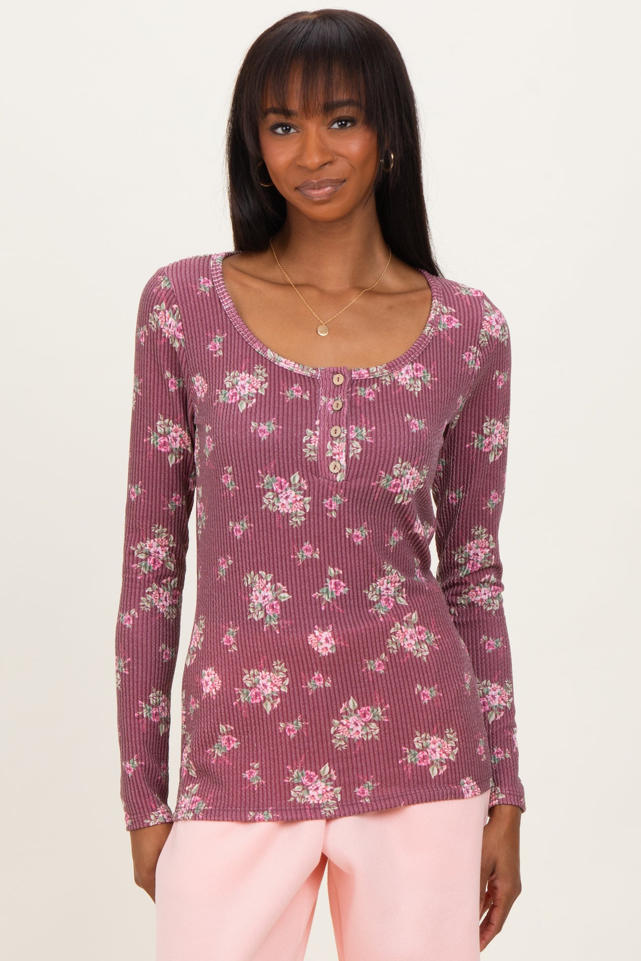 woman wearing a burgundy floral long sleeve scoop neck top with button details and ribbed texture