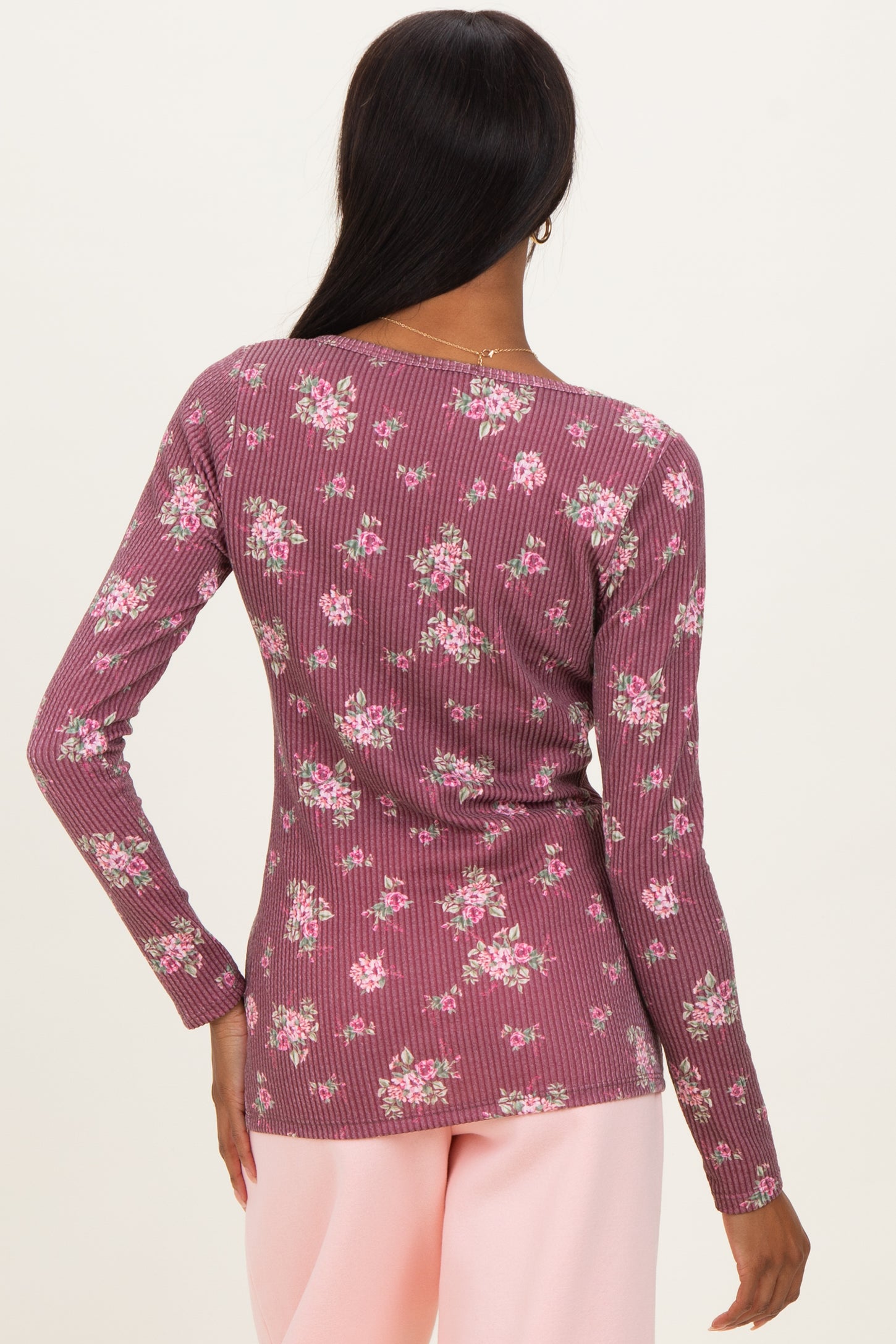 woman wearing a mauve ribbed long sleeve top with a floral print from the back