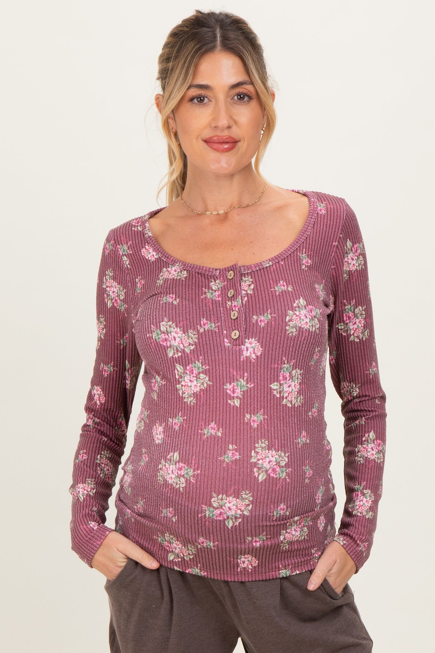 woman wearing a mauve floral maternity top with long sleeves and button details, showing her baby bump