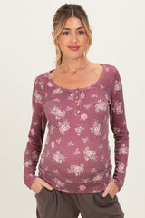 woman wearing a mauve floral maternity top with long sleeves and button details, showing her baby bump
