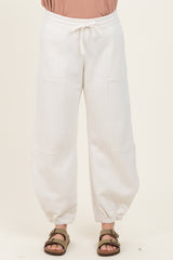 woman wearing cream-colored wide-leg sweatpants with elastic cuffs and drawstring waist
