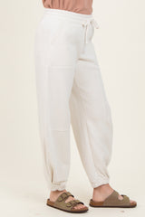 woman wearing white jogger pants with side pockets and cuffed ankles, paired with a pink top and sandals
