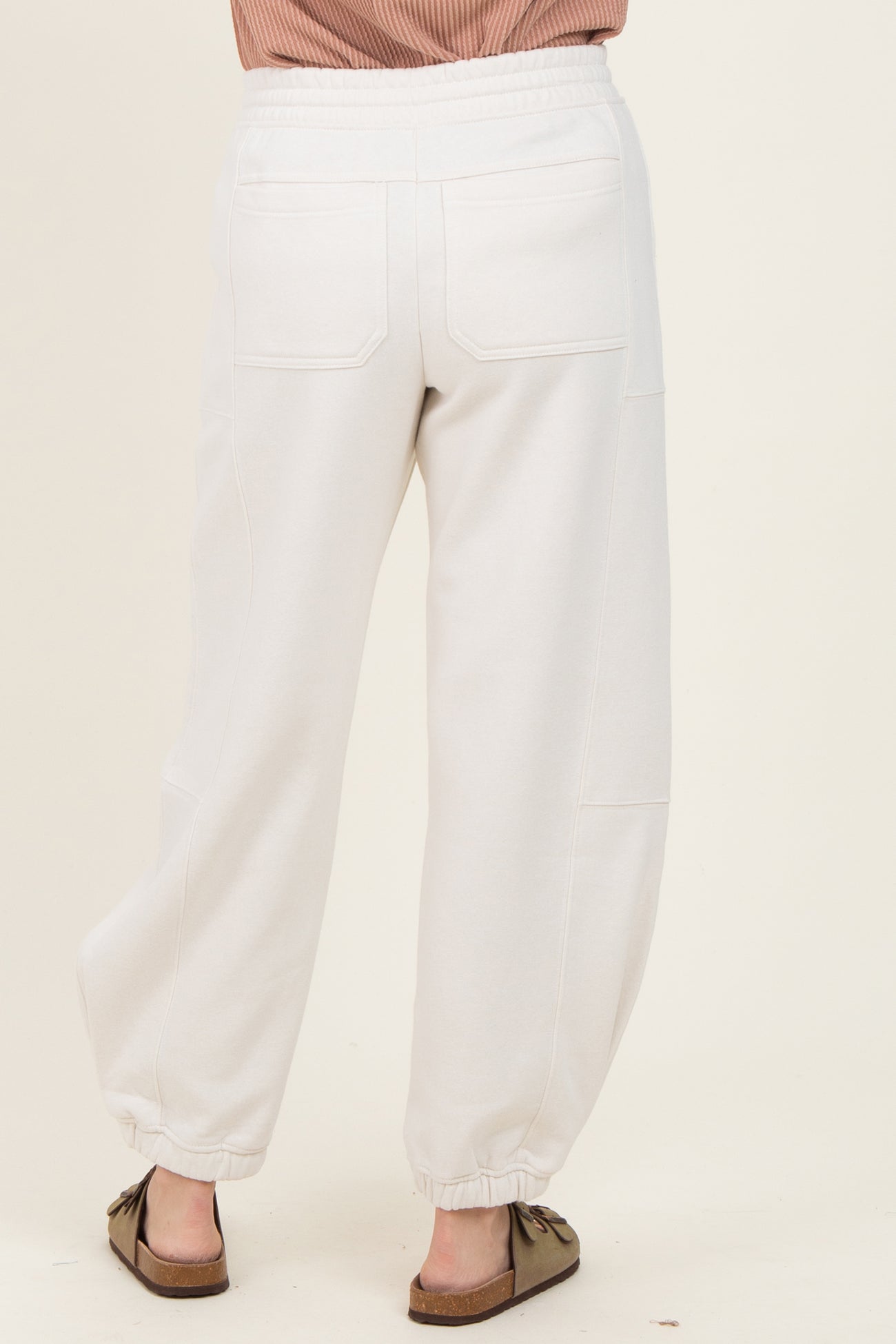 woman wearing light grey cropped jogger pants with a relaxed fit and elasticized cuffs, view from the back