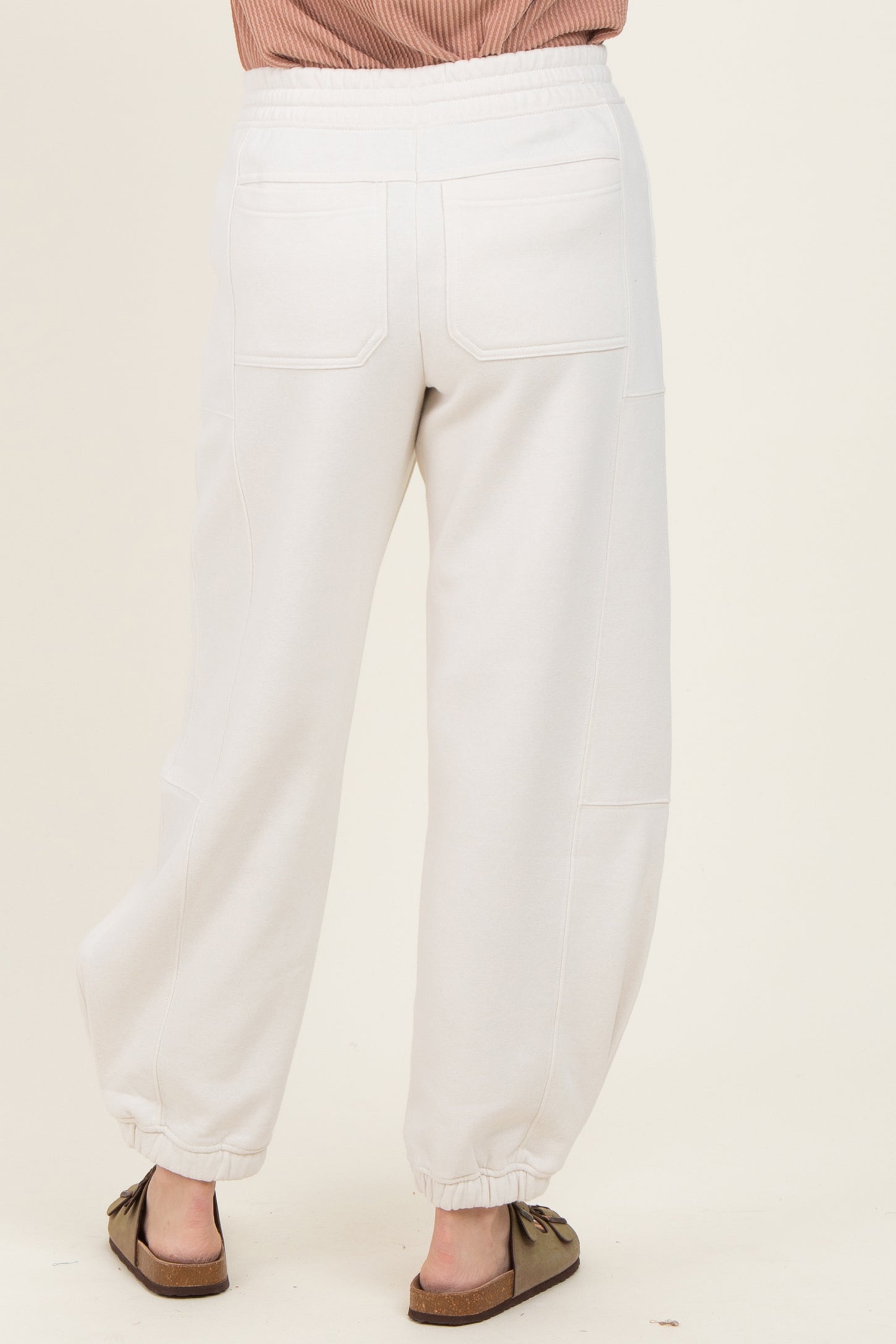 woman wearing light grey cropped jogger pants with a relaxed fit and elasticized cuffs, view from the back