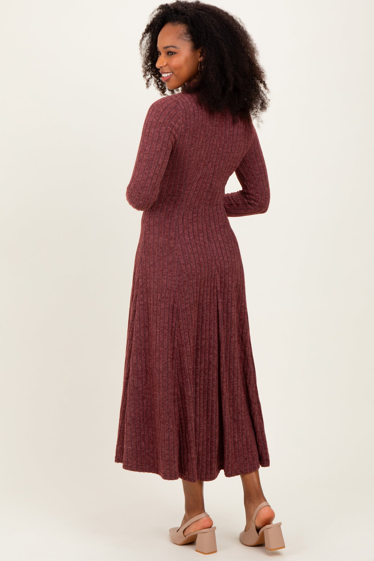 woman wearing a ribbed burgundy long sleeve midi dress, showing the back and flared skirt detail