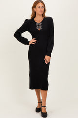 woman wearing a black ribbed long sleeve midi dress with a decorative necklace and posing with one hand on her hip