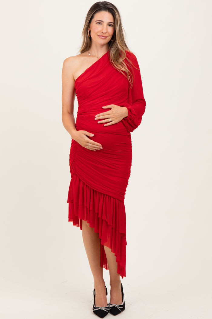 woman wearing a red one-shoulder maternity dress with ruching and a ruffled hem, holding her baby bump