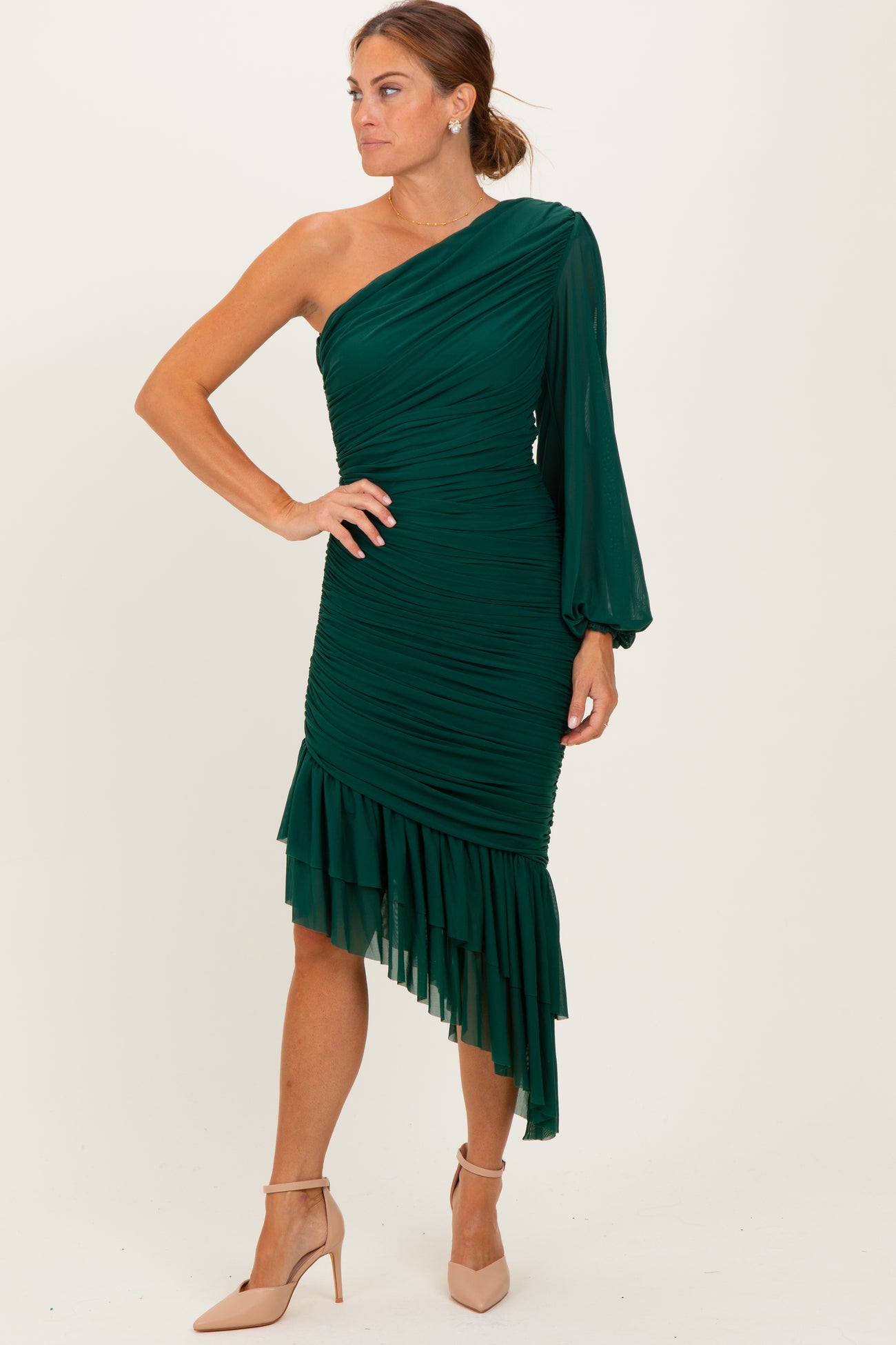 woman wearing a green one-shoulder ruched dress with a flounced hem and bell sleeve, posing elegantly