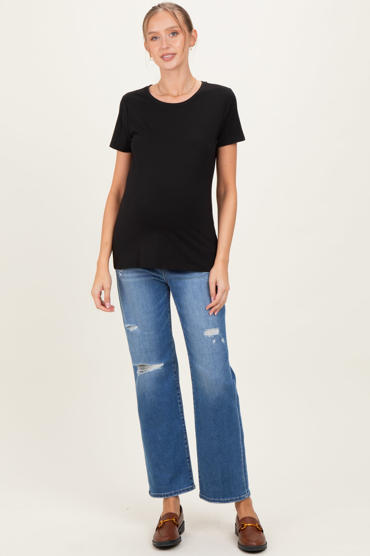 woman wearing a black short sleeve maternity top and distressed blue jeans with a visible baby bump
