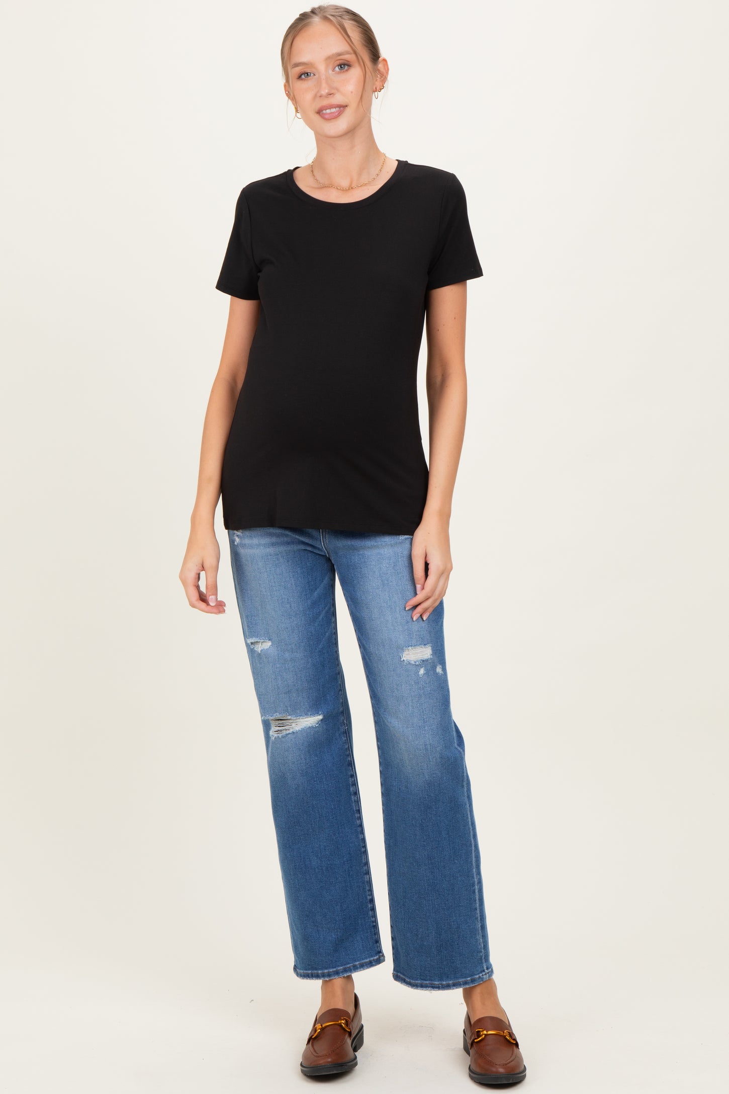 woman wearing a black short sleeve maternity top and distressed blue jeans with a visible baby bump