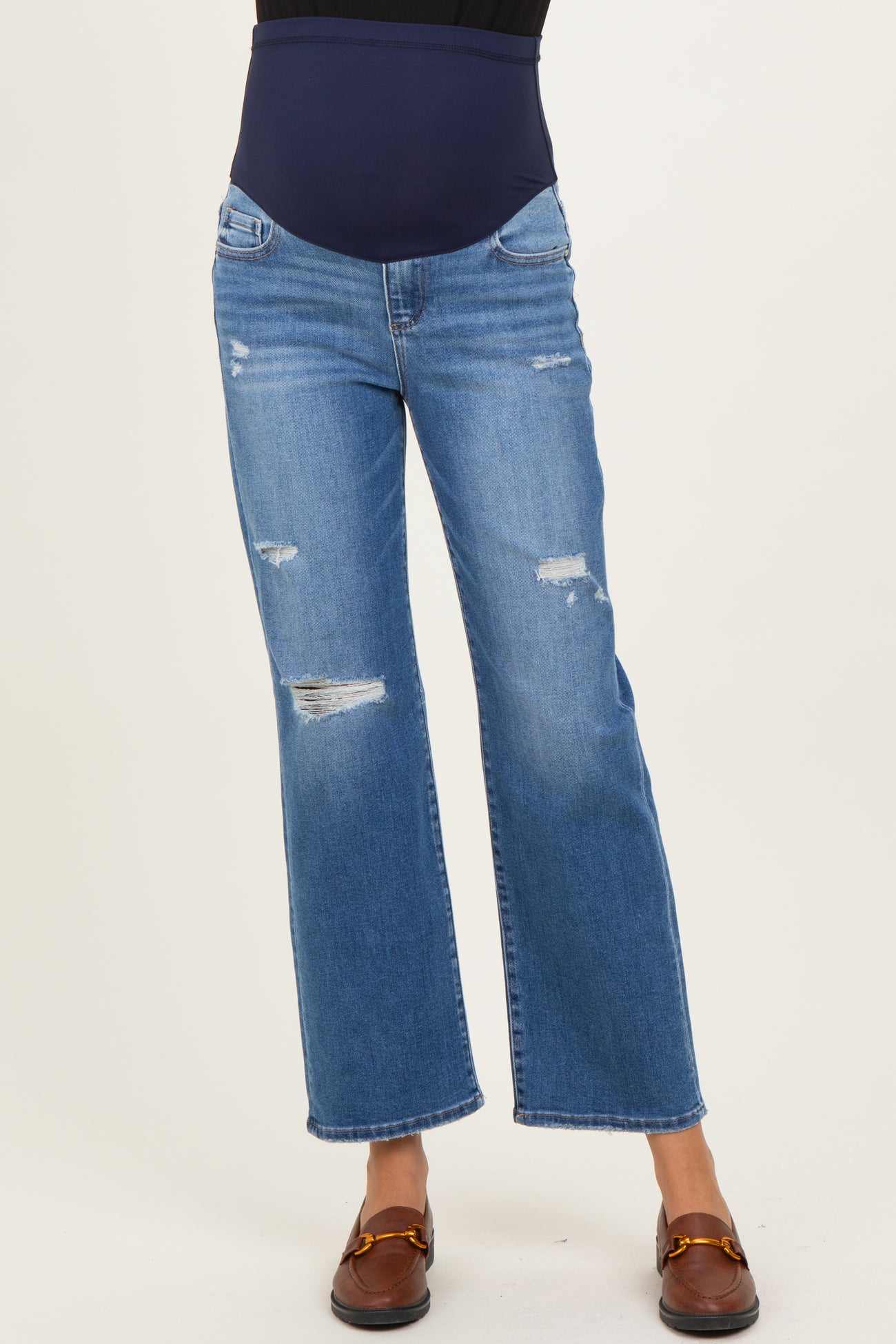 woman wearing light blue distressed maternity jeans with a dark blue over-the-bump waistband