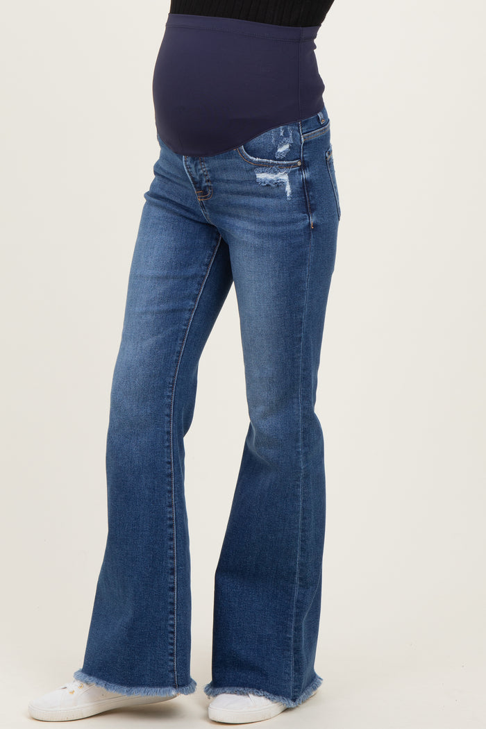 woman wearing dark blue maternity flared jeans with a distressed finish and a supportive over-the-bump waistband