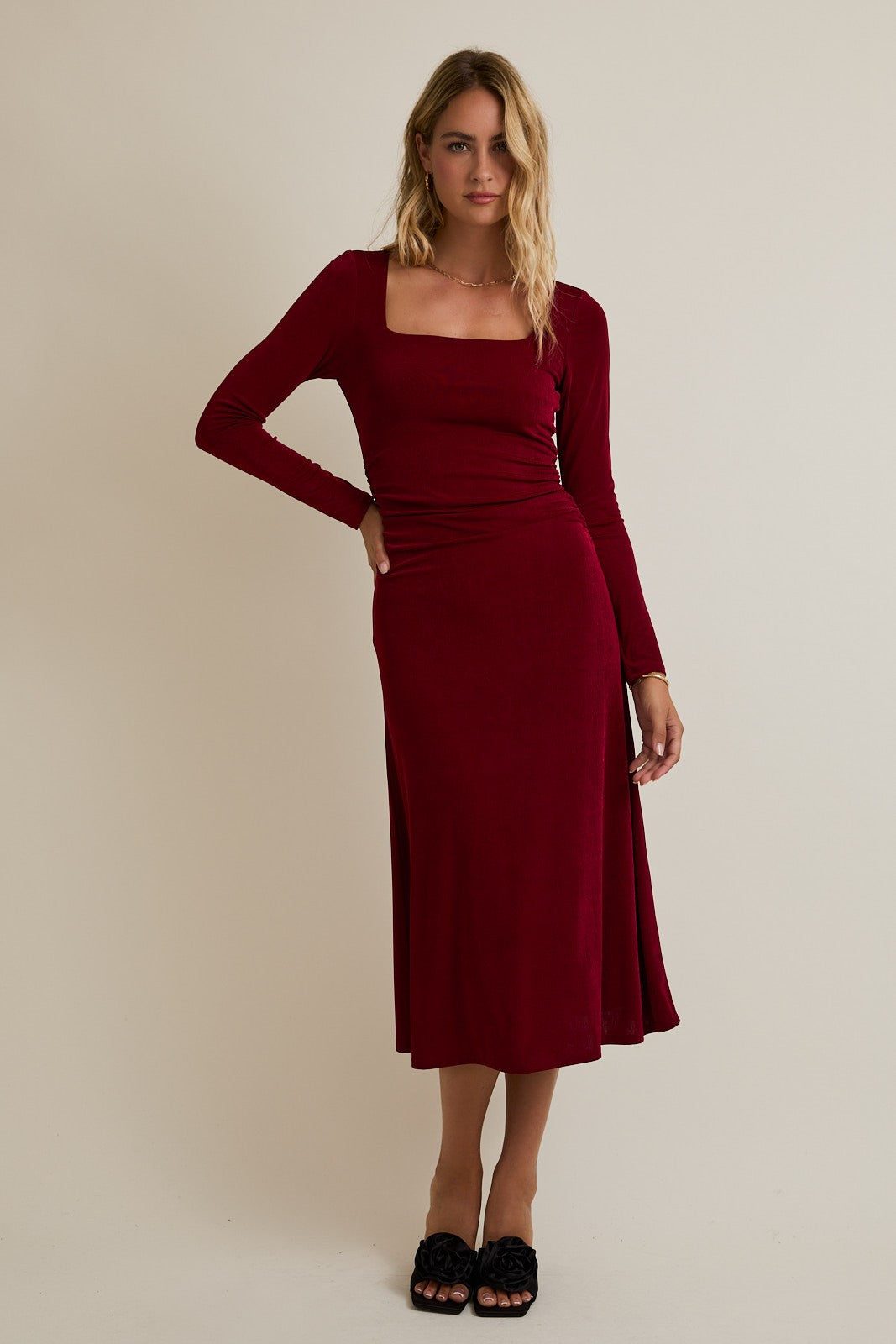 woman wearing a burgundy long sleeve midi dress with a square neckline and a side split
