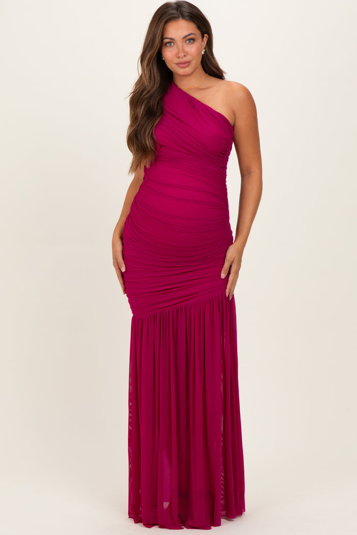woman wearing a fuchsia one-shoulder maternity gown with ruched detailing and a flowing skirt, showcasing her baby bump