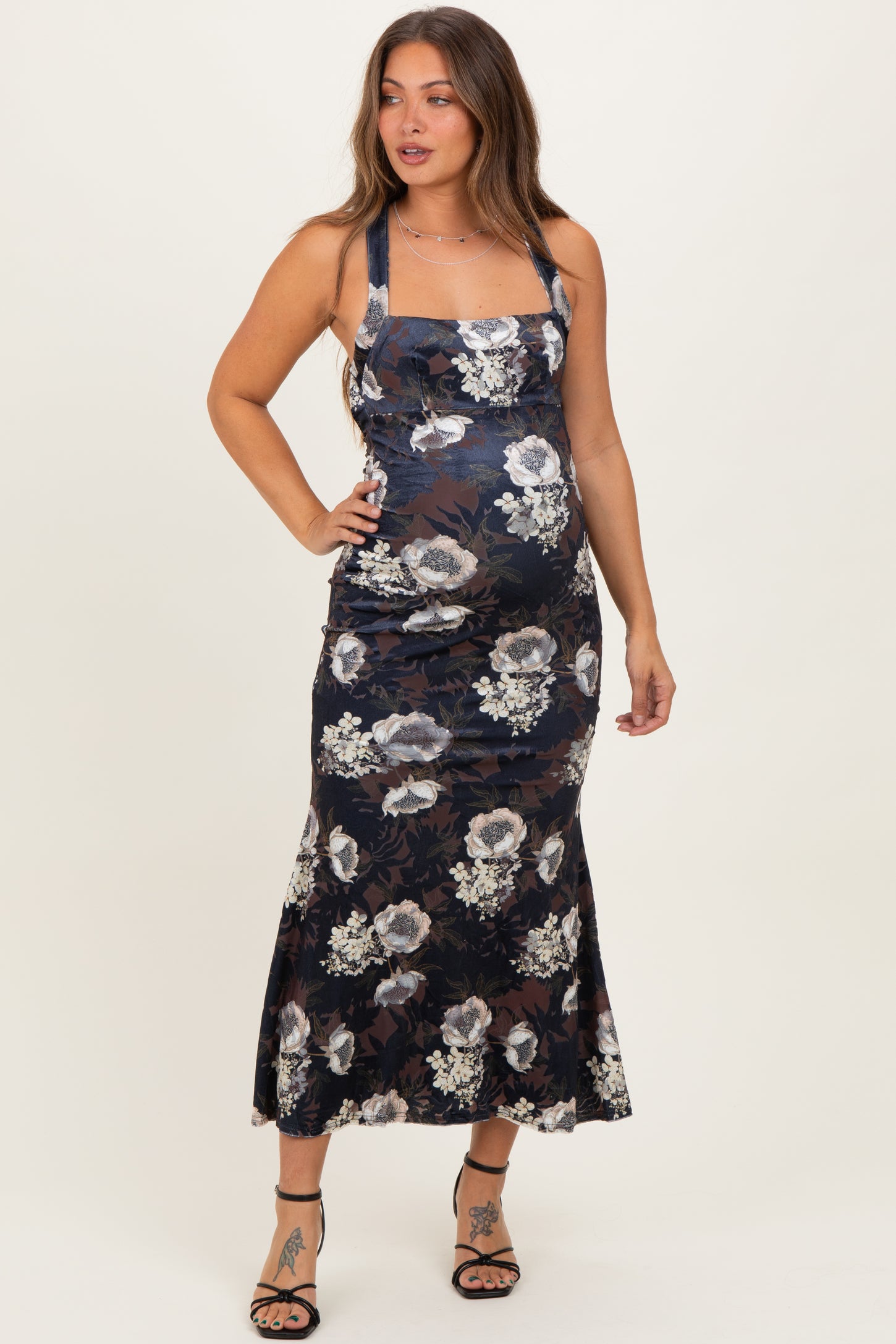 woman wearing a navy floral maternity maxi dress with a square neckline and fitted silhouette, showcasing her baby bump