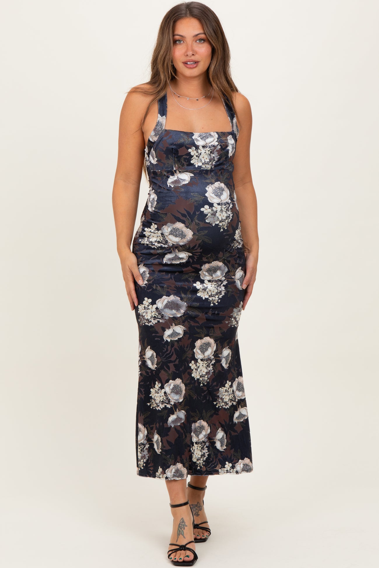 woman wearing a floral patterned navy blue maternity dress with a fitted silhouette and square neckline