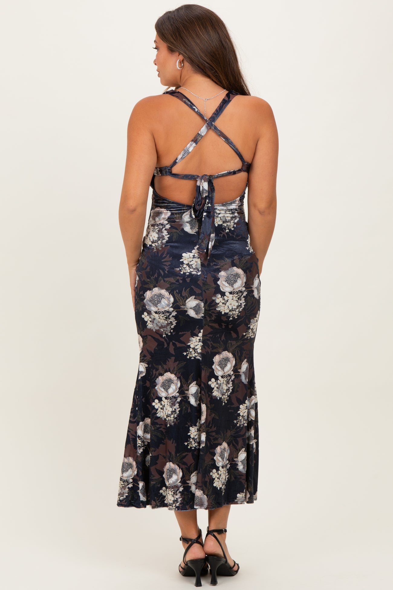 woman wearing a navy floral print maternity dress with a flared skirt and crisscross back straps
