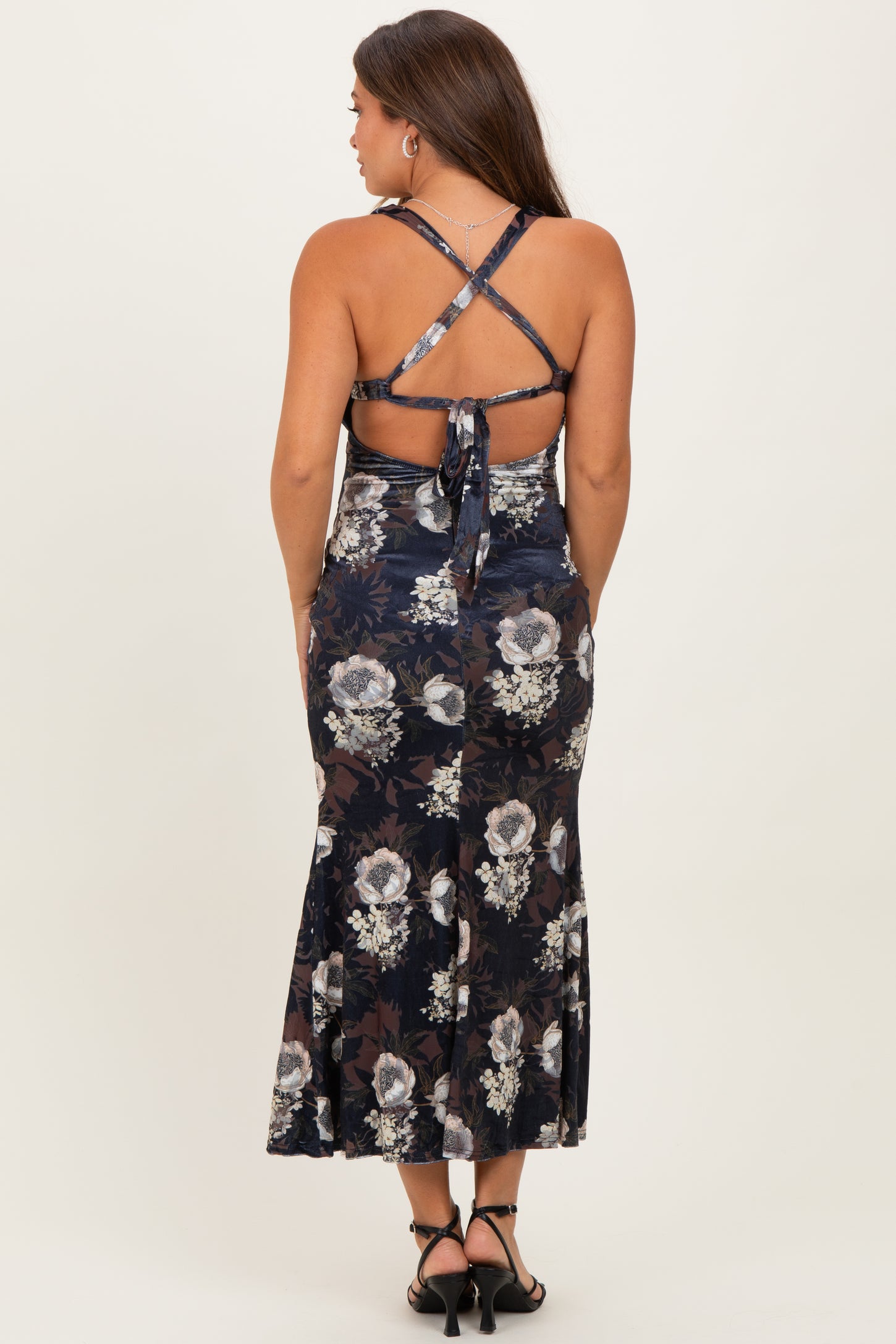 woman wearing a navy floral print maternity dress with a flared skirt and crisscross back straps