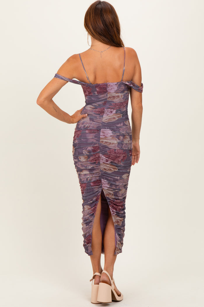 woman wearing a purple floral ruched bodycon dress with off-the-shoulder straps and a thigh-high slit
