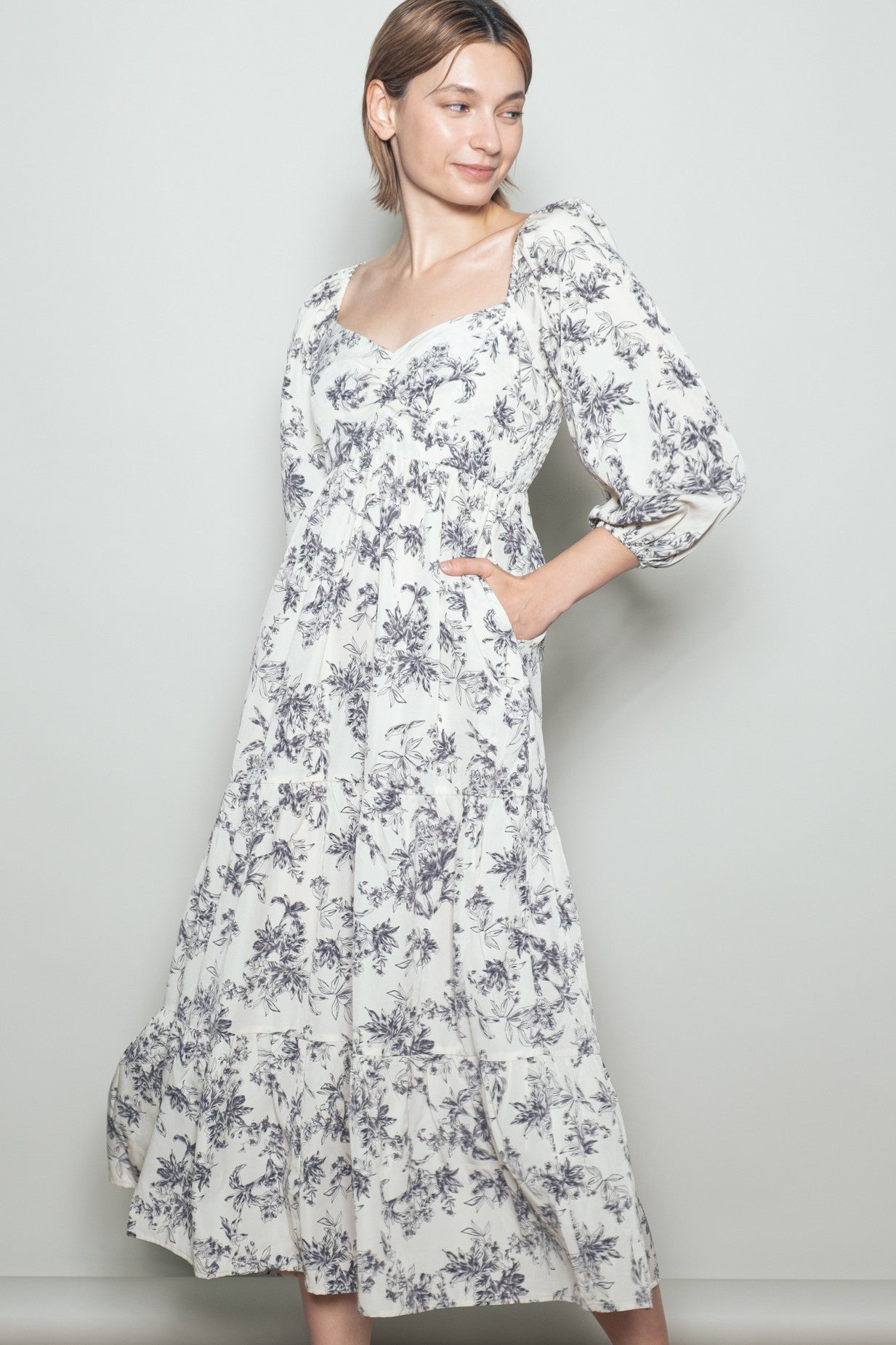 woman wearing a white floral print maxi dress with puff sleeves and side pockets