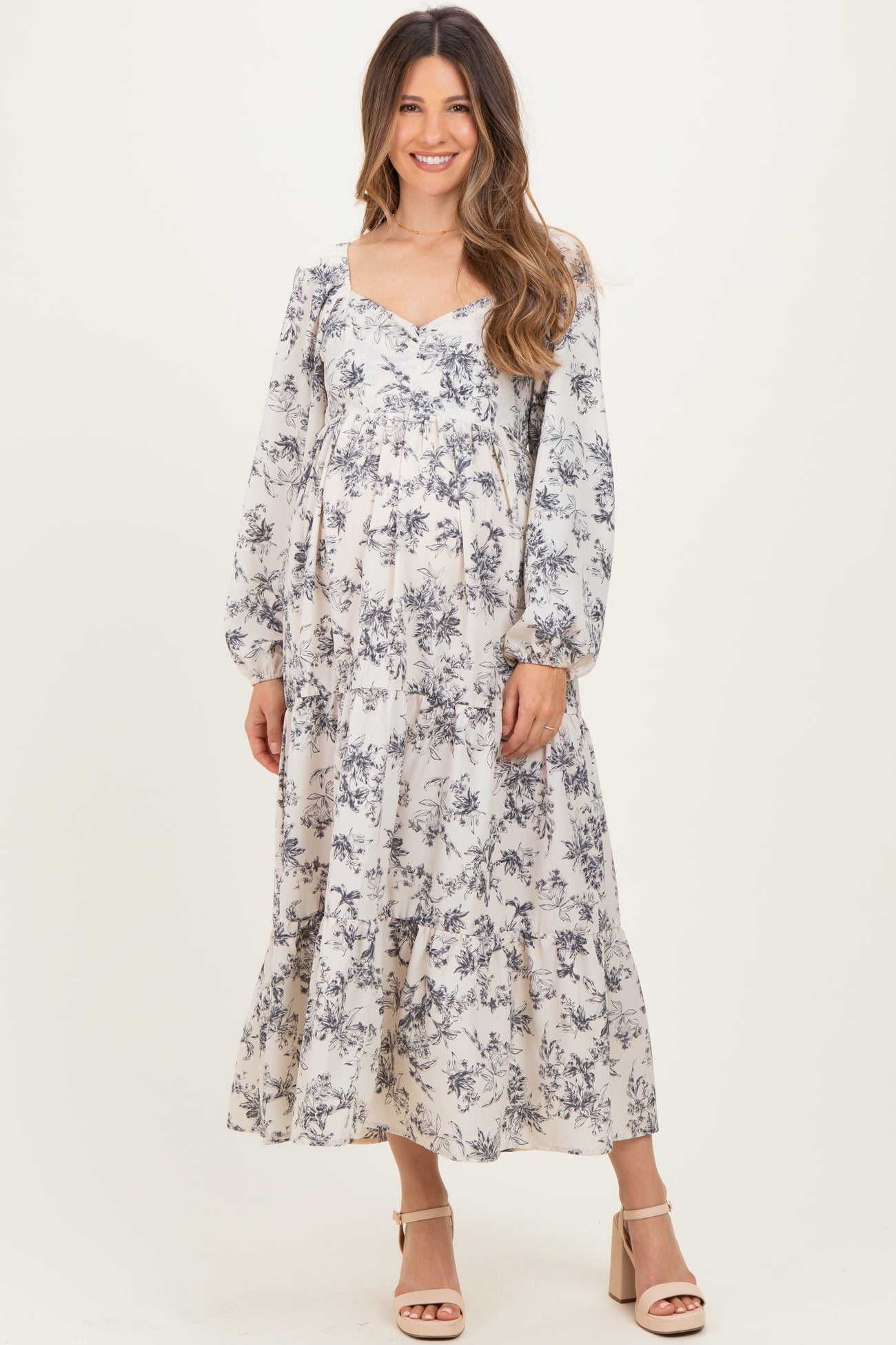woman wearing a long sleeve floral maternity dress with a flowing skirt and visible baby bump