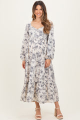 woman wearing a long sleeve floral maternity dress with a flowing skirt and visible baby bump