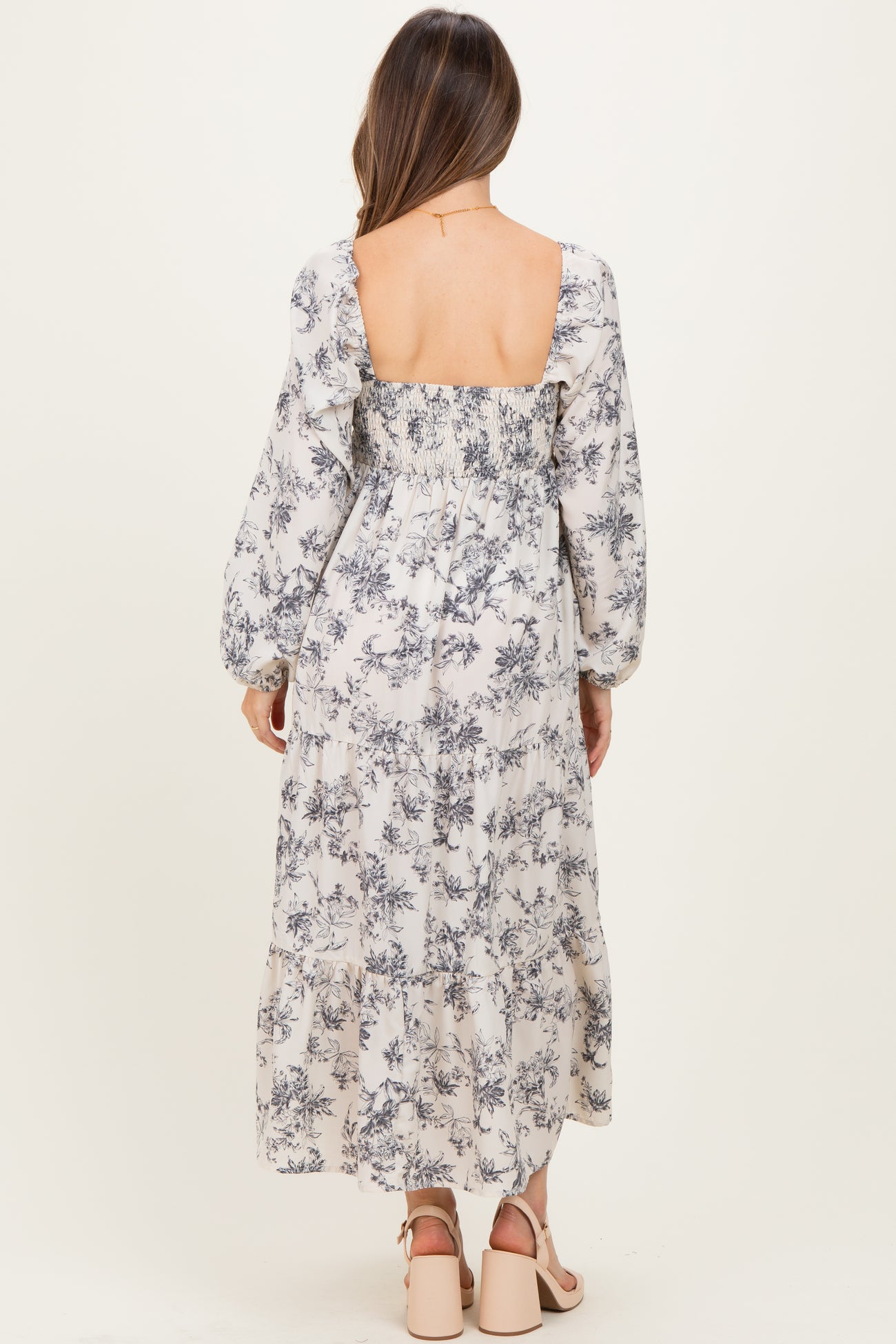woman wearing a floral print maternity maxi dress with a smocked back and long sleeves