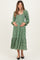 woman wearing a green floral maternity dress with long sleeves and a tiered skirt, holding her baby bump