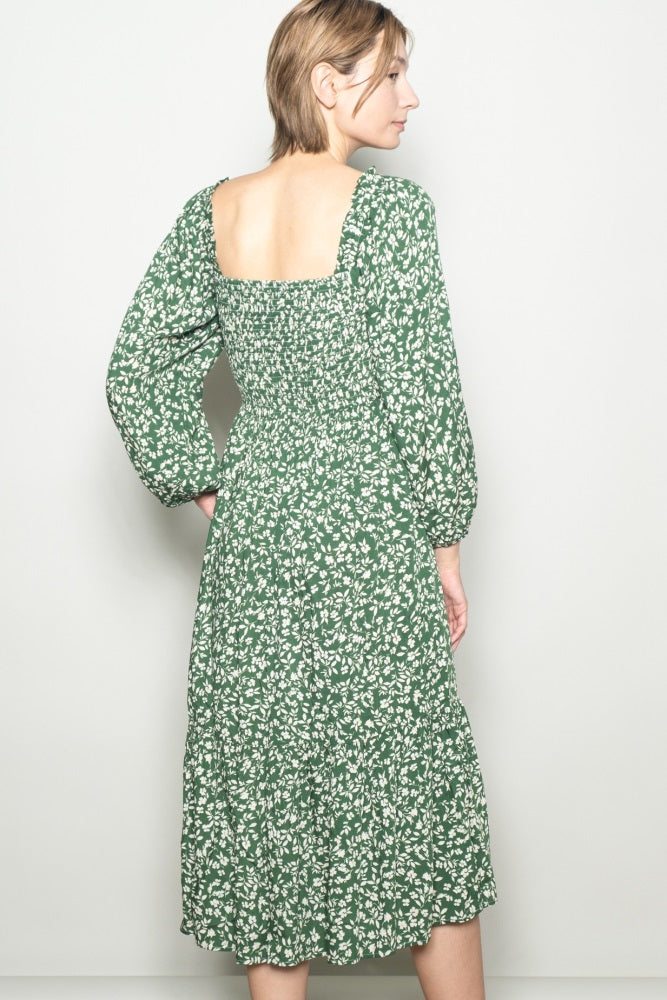 woman wearing a green floral midi dress with a square back and puff sleeves, viewed from the back