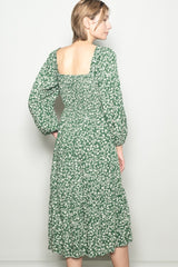 woman wearing a green floral midi dress with a square back and puff sleeves, viewed from the back