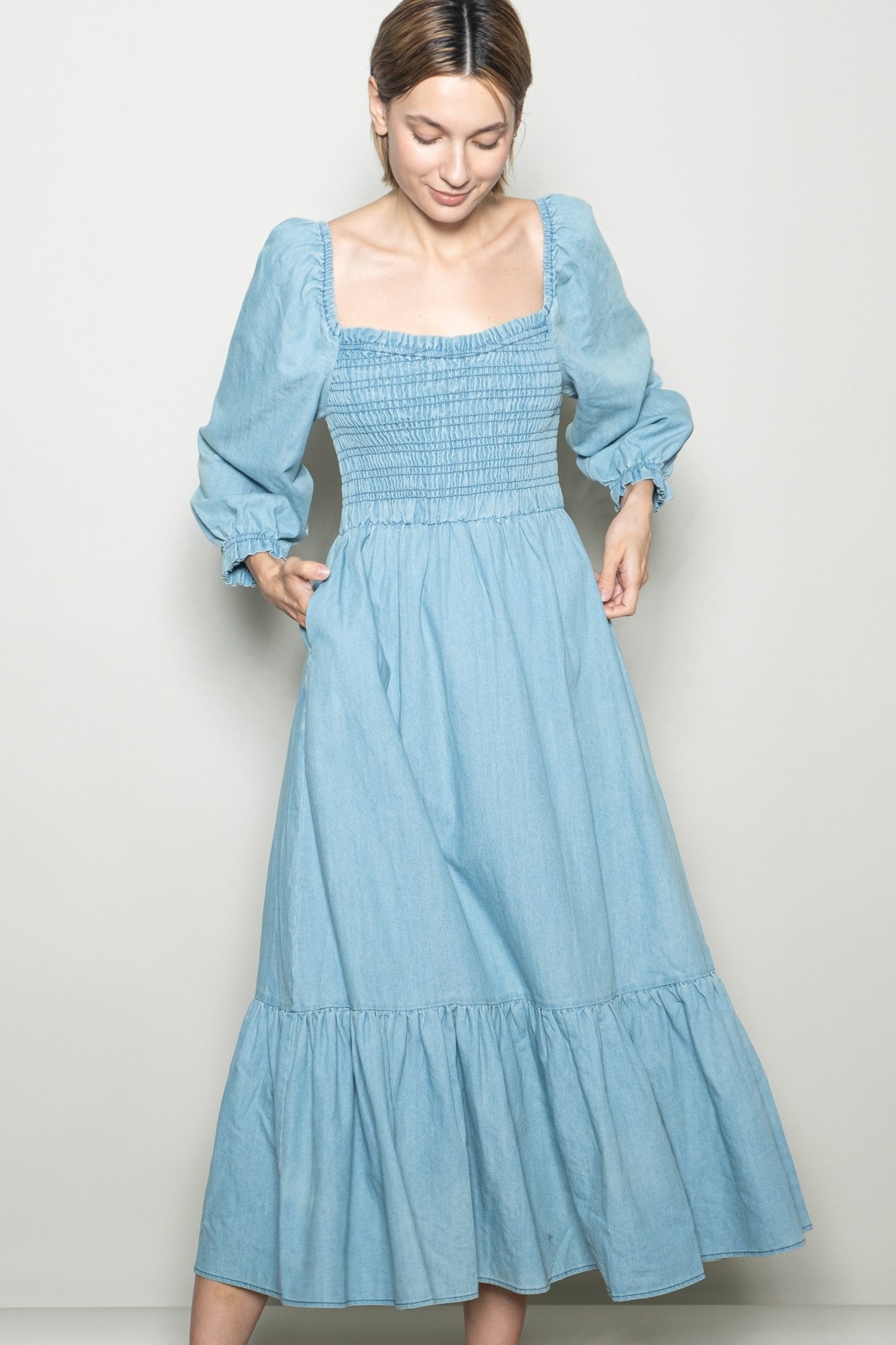 woman wearing a light blue denim maxi dress with a smocked bodice and puff sleeves