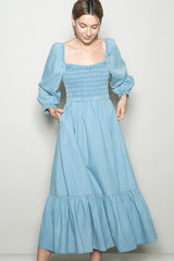 woman wearing a light blue denim maxi dress with a smocked bodice and puff sleeves