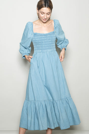 woman wearing a light blue denim maxi dress with a smocked bodice and puff sleeves