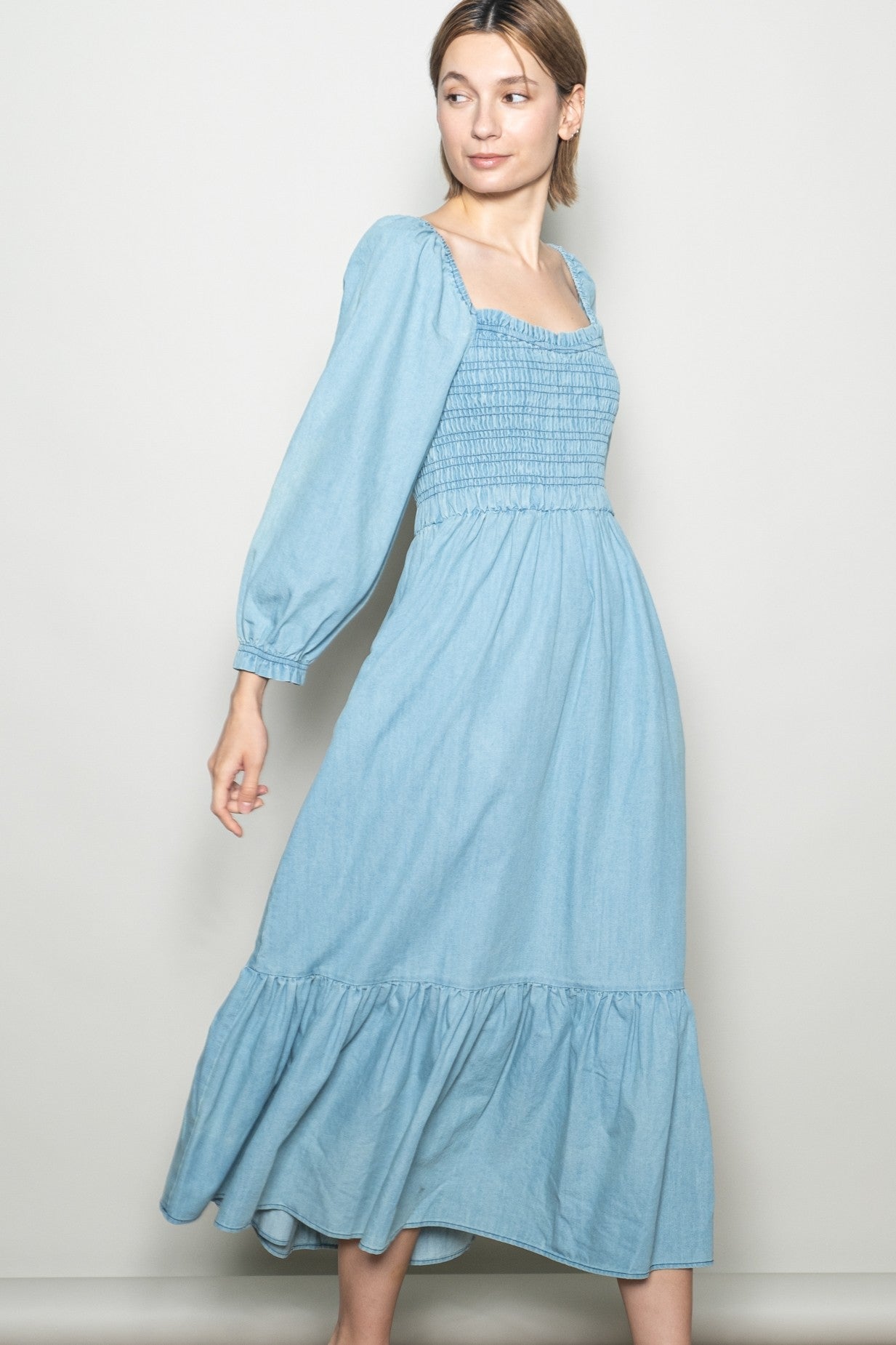 woman wearing a light blue smocked bodice long sleeve maxi dress with a tiered ruffle hem