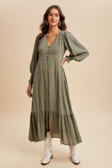 woman wearing an olive green long sleeve midi dress with a tiered skirt and button details, styled with white boots