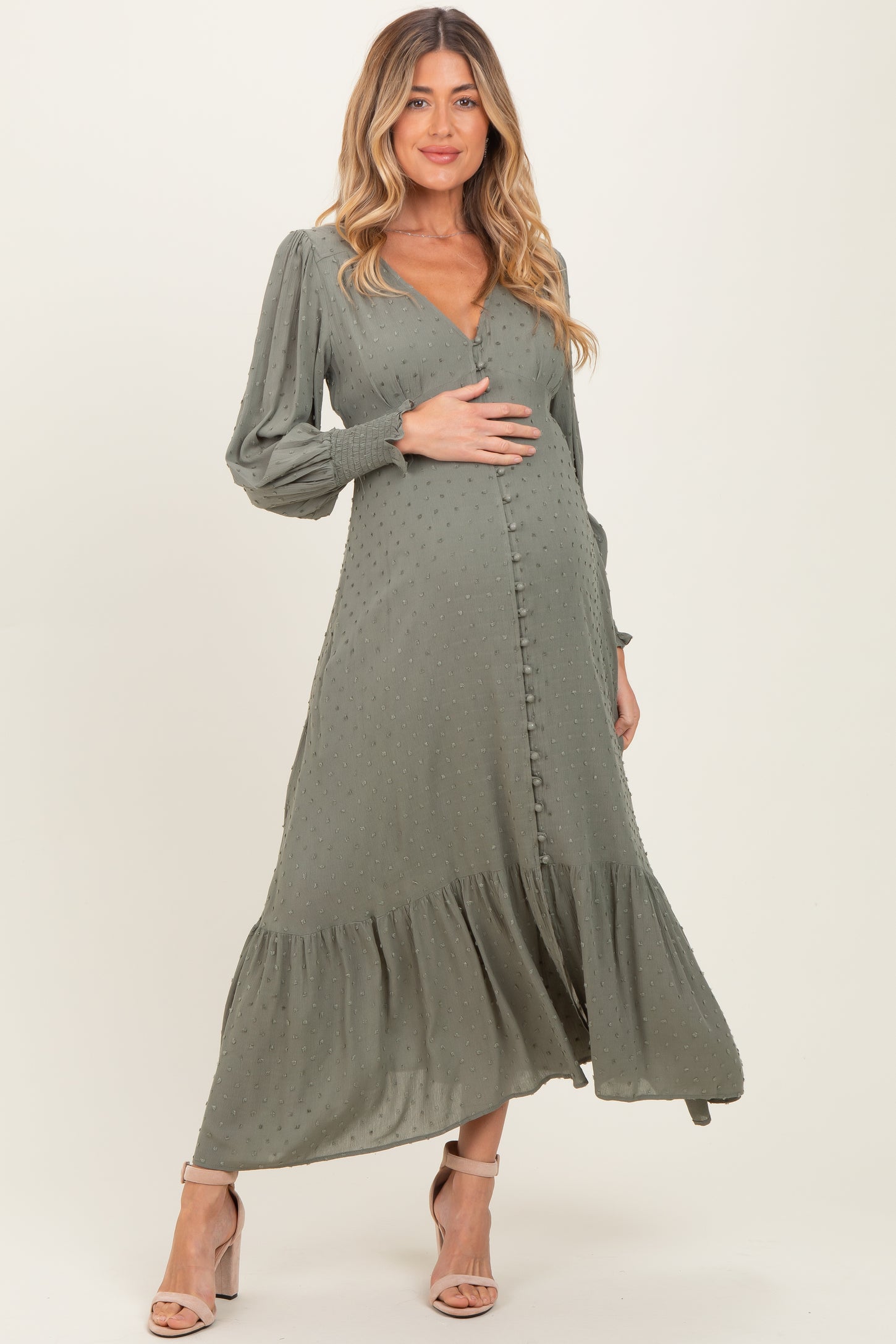 woman wearing a dusty green maternity dress with long sleeves and a tiered hem, highlighting her baby bump