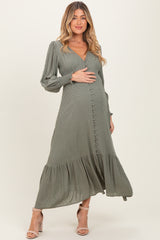 woman wearing a dusty green maternity dress with long sleeves and a tiered hem, highlighting her baby bump
