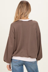 woman wearing a brown maternity sweater with balloon sleeves and a ribbed hem, view of the back