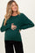woman wearing a green cable knit maternity sweater and holding her baby bump