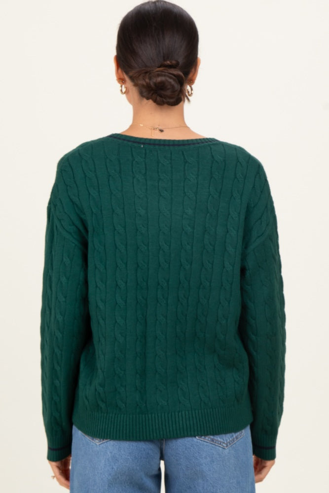 woman wearing a dark green cable knit sweater with a relaxed fit and crew neckline, seen from the back