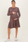woman wearing a mauve ribbed long sleeve maternity dress with a tiered skirt and holding her baby bump