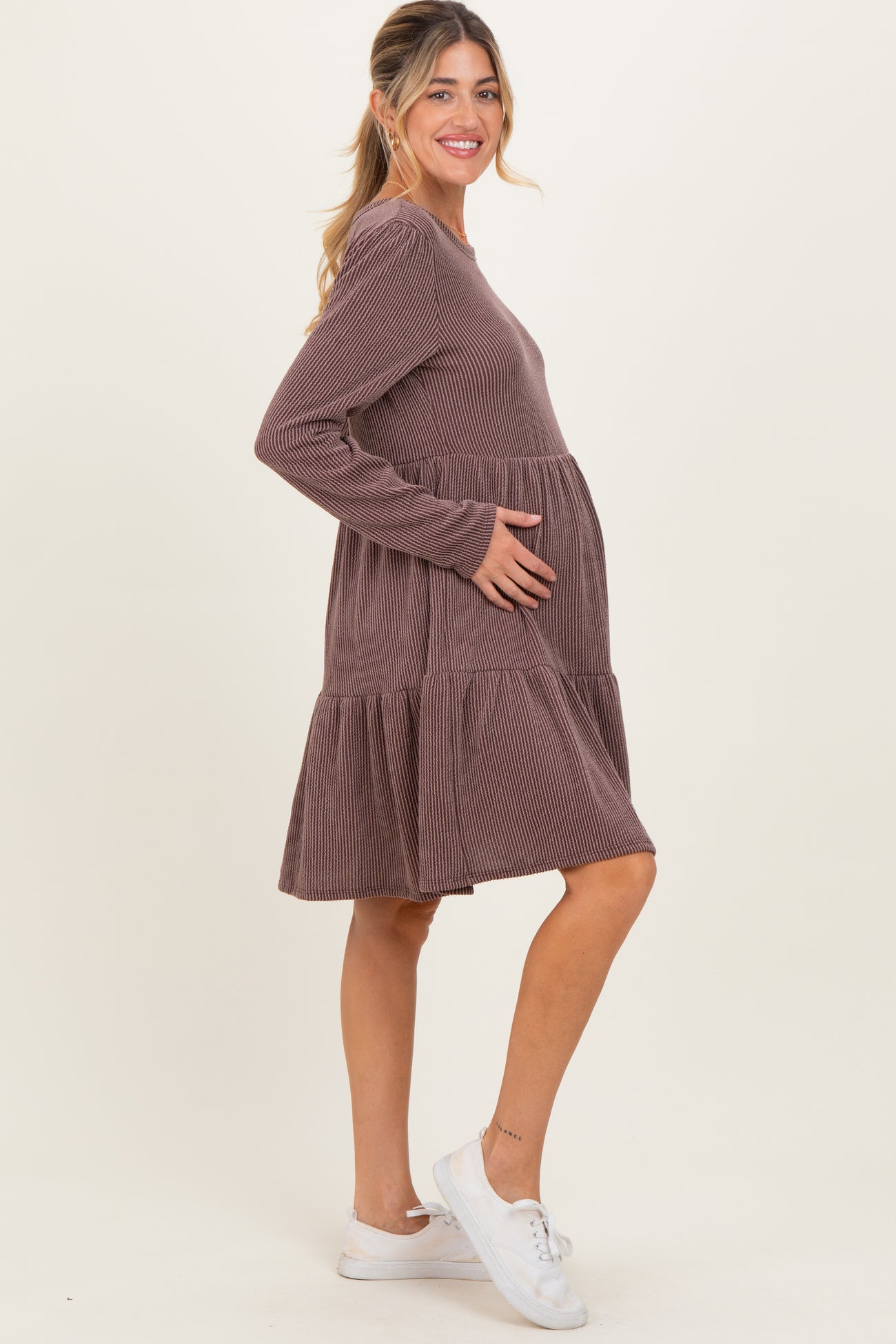 woman wearing a brown striped maternity dress with a tiered skirt and showing her baby bump