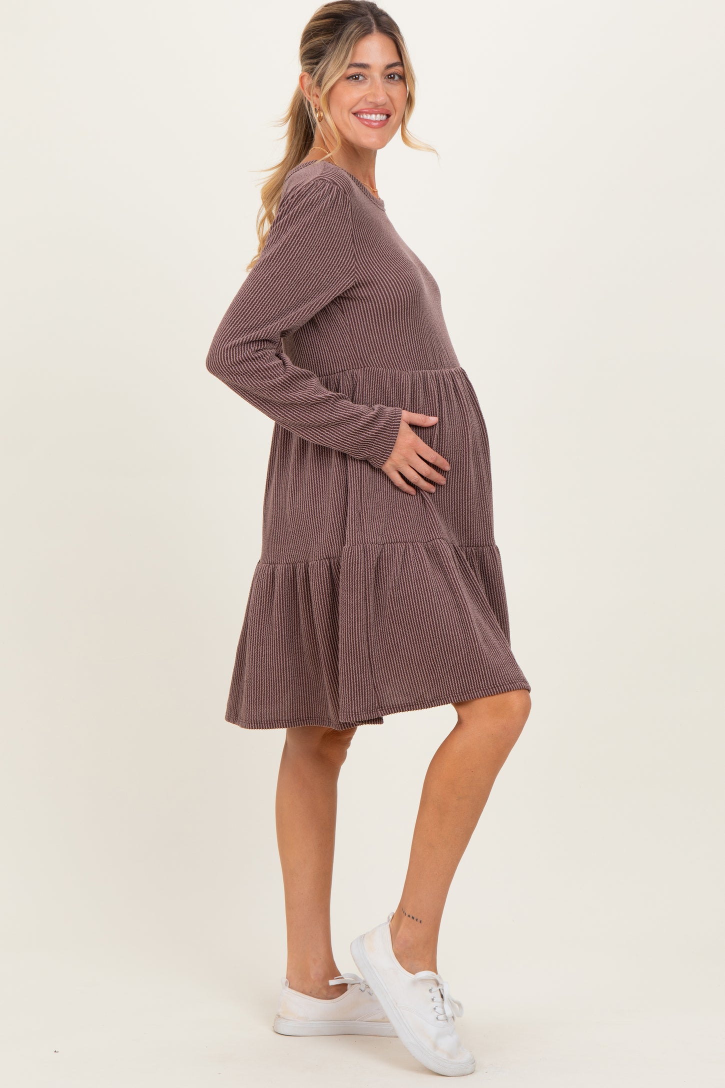 woman wearing a brown striped maternity dress with a tiered skirt and showing her baby bump