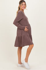 woman wearing a brown striped maternity dress with a tiered skirt and showing her baby bump