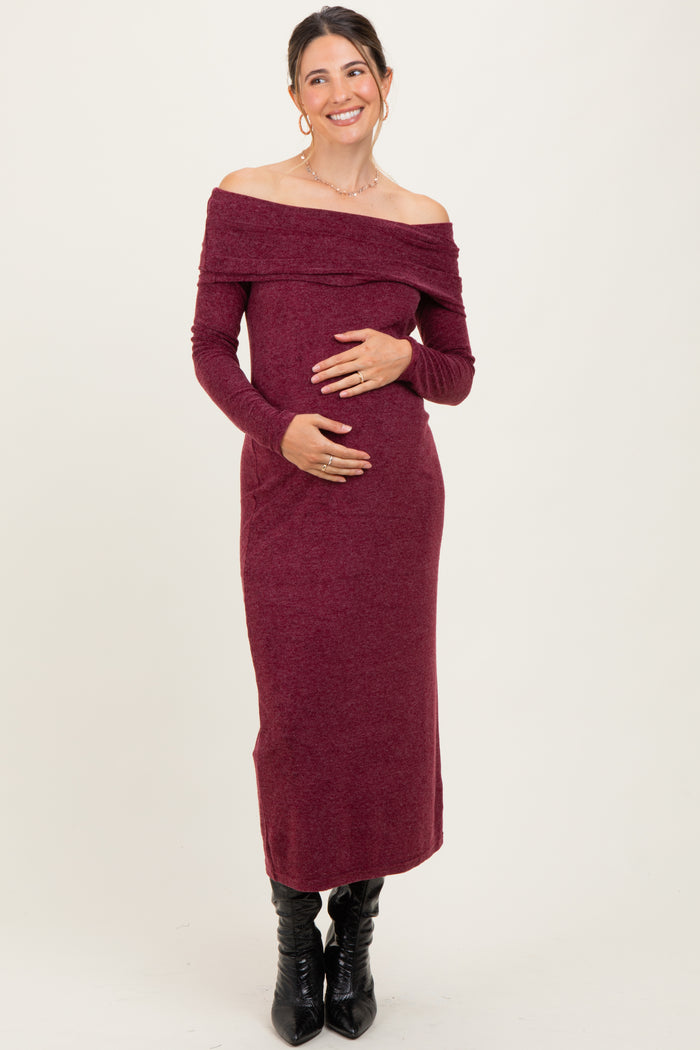 woman wearing a burgundy off-shoulder maternity dress and holding her baby bump