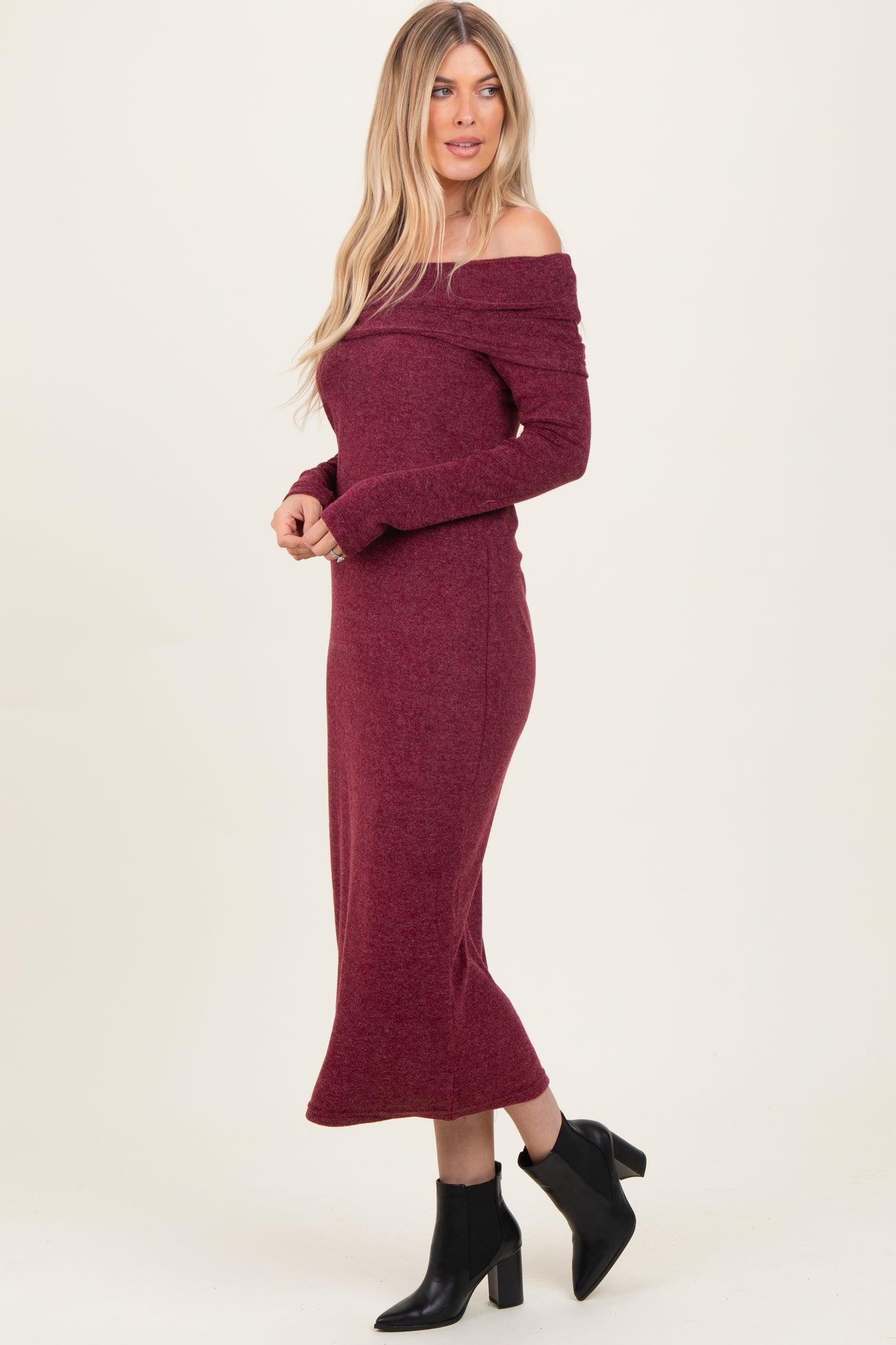 woman wearing a burgundy off-the-shoulder long sleeve midi dress paired with black ankle boots