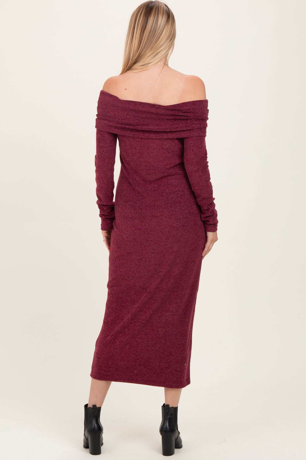 woman wearing a burgundy off-the-shoulder long sleeve midi dress with a fitted silhouette and ribbed detailing