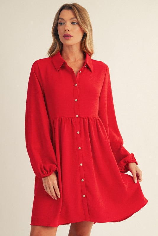 woman wearing a bright red long sleeve button-up dress with a fitted waist and flared skirt