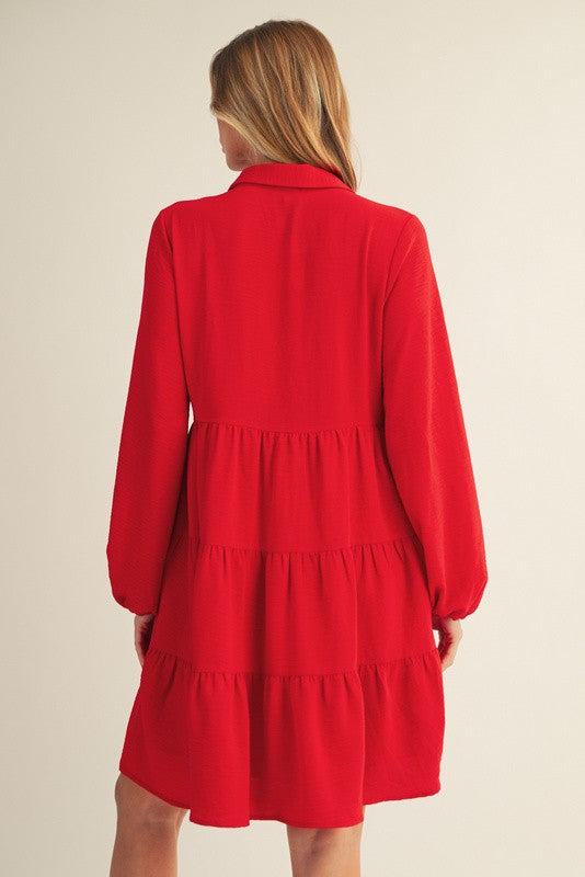 woman wearing a red tiered dress with long sleeves, shown from the back
