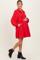 woman wearing a red maternity dress with a button-up front and pockets, showing her baby bump
